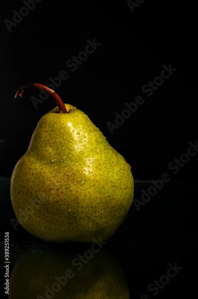 Obraz Close-up of fresh wet green pear on black background with reflection