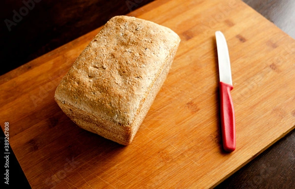 Obraz Homemade bread in the shape of a brick on a cutting board with a red knife