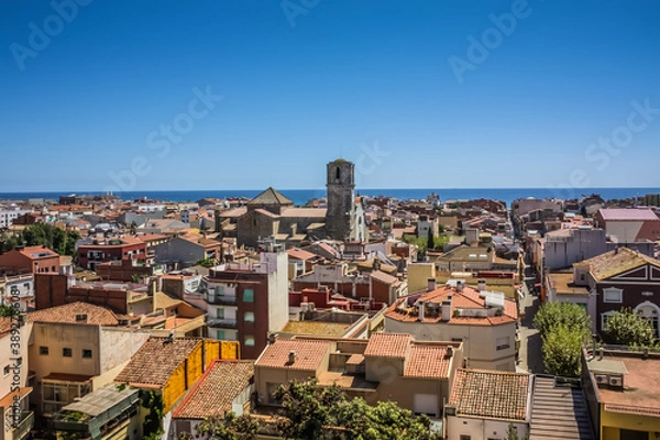 Fototapeta View over the roofs of old town Malgrat de Mar (Spain) from the hill with Mediterranean sea in the background and the Cathedral of the Coast in the middle