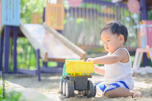 Fototapeta Asian Baby boy playing with sand in a sandbox,Healthy active baby outdoors plays toy