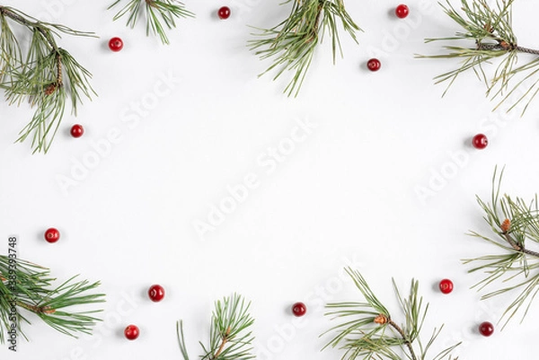 Fototapeta Christmas background with cranberries and pine branches on a white backdrop. Top view, flat lay, copy space