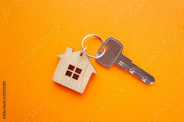 Fototapeta Key and house shaped keychain arrangement on orange background. Top view, flat lay. Real estate, insurance concept, mortgage, buy sell house, realtor concept.