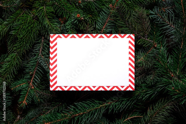 Fototapeta Christmas tree branches with paper card note. Nature New Year concept. Merry Christmas card, background. Congratulations, holidays, celebration. Mock up, copy space, flat lay. Red, green and white.