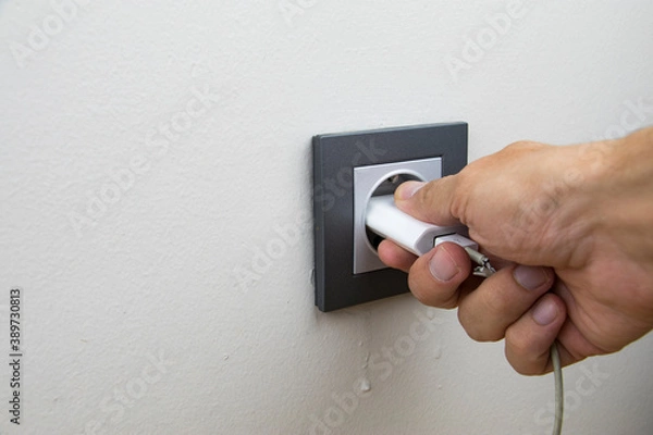Fototapeta close up photo revealing that a person is plugging in or unplugging to charge/discharge of a battery