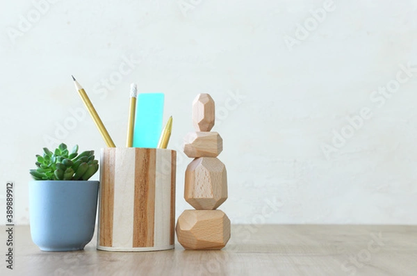 Fototapeta Stylish and minimal workplace with plant, pencils stand and dummy over wooden desk work
