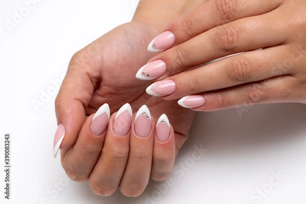 Fototapeta Wedding french sharp white manicure with crystals on long sharp nails close-up on a white background