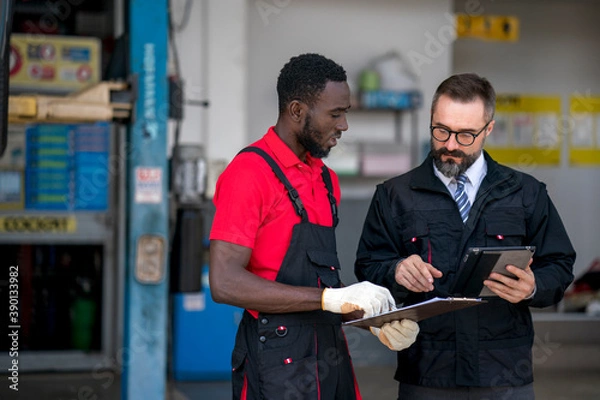 Obraz The mechanic discuss with his chief during car damage inspection at the garage 