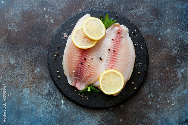 Fototapeta Raw fish tilapia fillet with spices and lemon slices