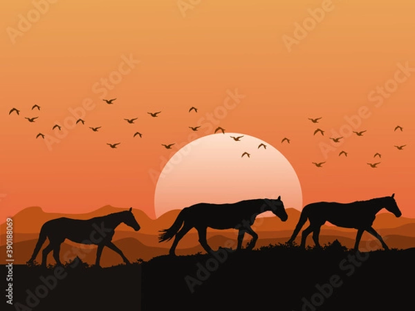 Obraz The silhouette of a herd of horses on the hills at sunset has mountains and orange sky as background