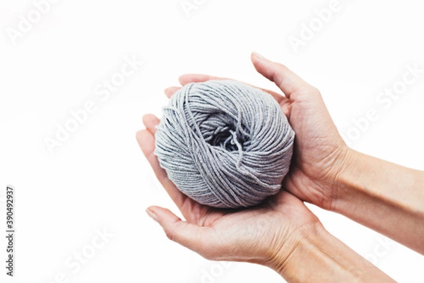 Fototapeta  Women's hobby. Crochet and knitting. Working space. Gray yarn the in hands on the yellow background. Hobby
