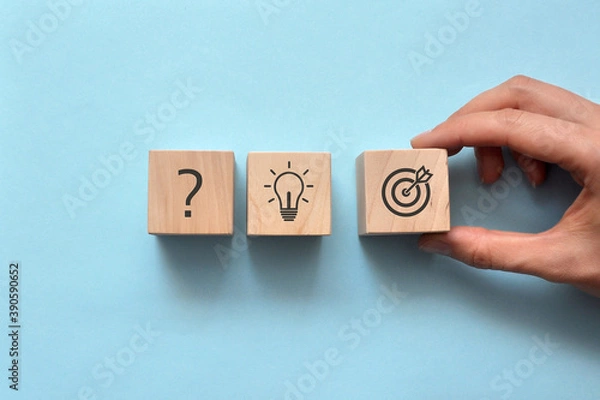 Fototapeta Wooden blocks with drawings of the question, light bulbs and a target on them. Symbol of the question, idea origin, and start of action