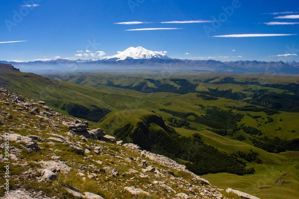 Fototapeta An excellent view from the plateau to the extinct volcano and the snowy peak of Mount Elbrus. Below is a green gorge