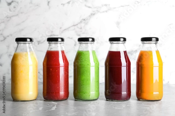 Fototapeta Bottles with delicious colorful juices on marble table