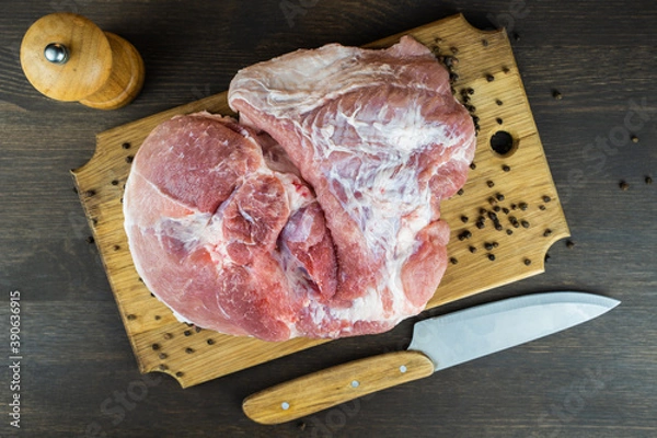 Fototapeta Juicy raw piece of meat with a knife and pepper on a wooden Board. The view from the top.