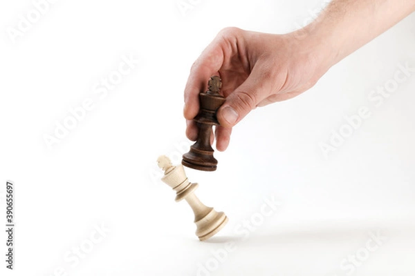 Fototapeta hand holds a chess king piece and defeats another king