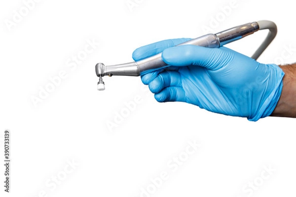Fototapeta A dentist doctor holds a dental instrument on a white isolated background. The hand with the tool close up