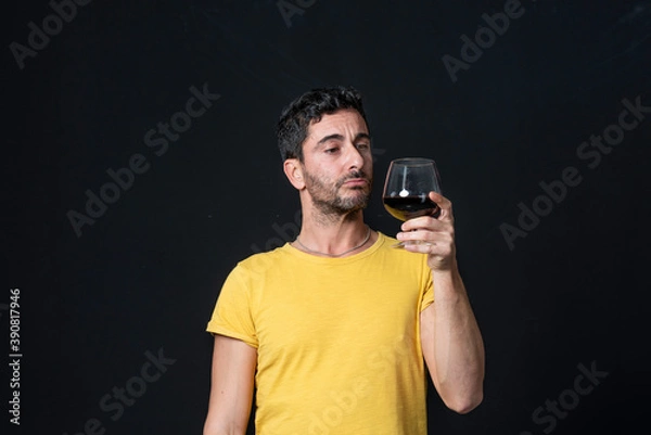 Obraz Man drinking red wine on black background