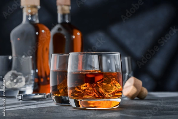 Fototapeta Two round glasses of whiskey with ice on a concrete table, on a blue background.