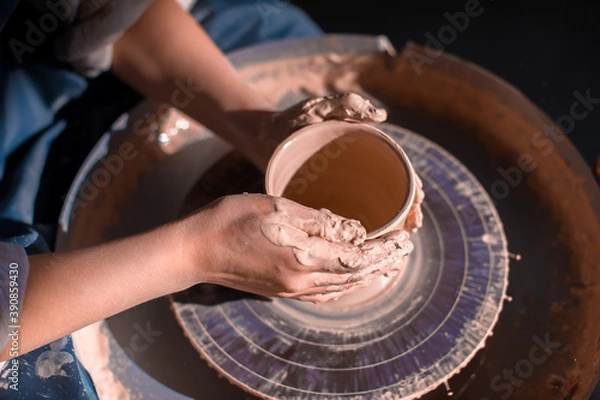 Fototapeta Professional potter making pottery, sculptor from wet clay on wheel. Concept of ceramic art. Close-up.