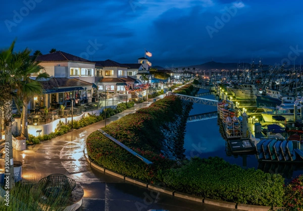 Obraz Ventura Harbor Village boardwalk is reflective and wet from the early morning rain with rain clouds reflected in harbor water.