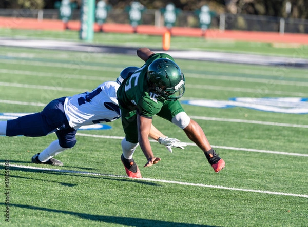 Fototapeta Football player making a tackle during a game