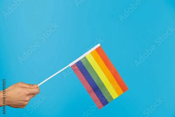 Fototapeta Hand with LGTB flag on blue background. Symbol lgtb