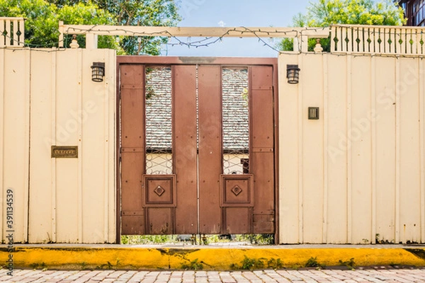 Obraz Door in a Wall Along a Sidewalk Leading into a Courtyard.
