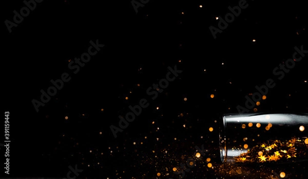 Fototapeta Champagne glass with bokeh and confetti on black background. Top horizontal view copyspace