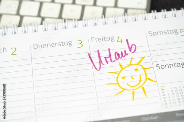 Fototapeta The entry of the German word for vacation and the drawing of a smiling sun in a desk calendar