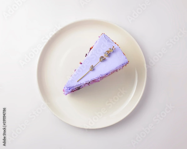 Fototapeta Cut lavander cake on a white plate. A piece of purple violet cake with lavander and berries served on a white plate.