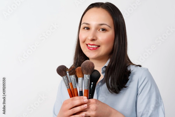 Fototapeta Woman makeup artist with set of brushes on white background.