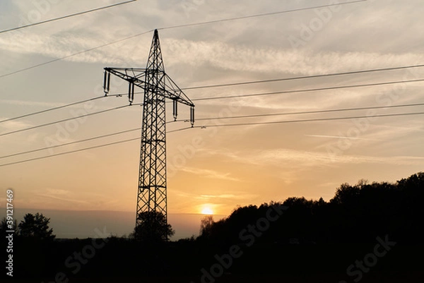 Fototapeta Transmission tower during sunset. Silhouette of a transmission tower during sunset. Silhouette of power lines during sunset.