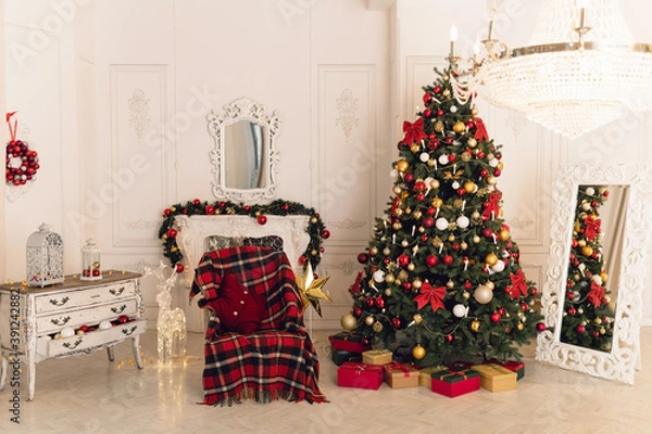 Fototapeta Christmas classic interior with christmas tree and a fireplace in traditional red color. Beautiful christmas decor. Happy new year concept.	