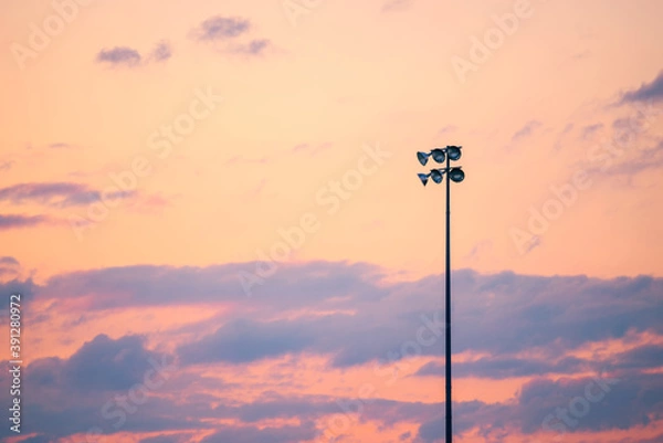 Fototapeta Single pole or column of spotlight or stadium light in arena with sunset beautiful sky and with copy space.