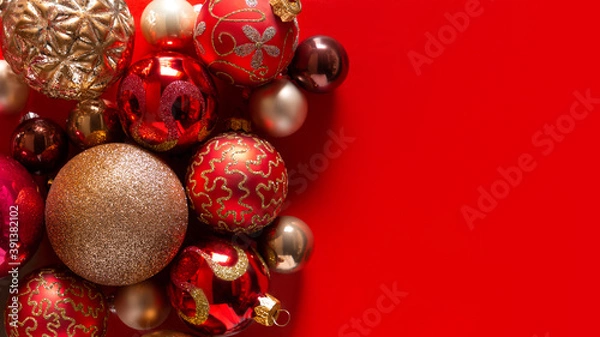 Fototapeta Banner with red background and red and gold Christmas balls, decoration on the left. Christmas card. Texture and pattern. Flat lay, top view, copy space. New year concept. Winter holidays