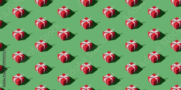 Fototapeta Christmas isometric pattern, background, banner. Minimal composition made of Christmas red gift box on a green background. Top view. Holiday New Year concept. Xmas presents, congratulations
