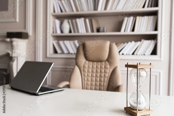 Fototapeta Business workplace with a sand wach and a laptop on the table. Timing and deadline concept.
