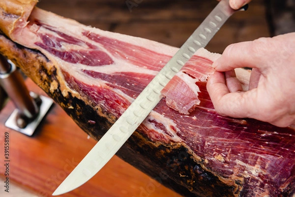 Obraz Manos cortando jamón ibérico con cuchillo