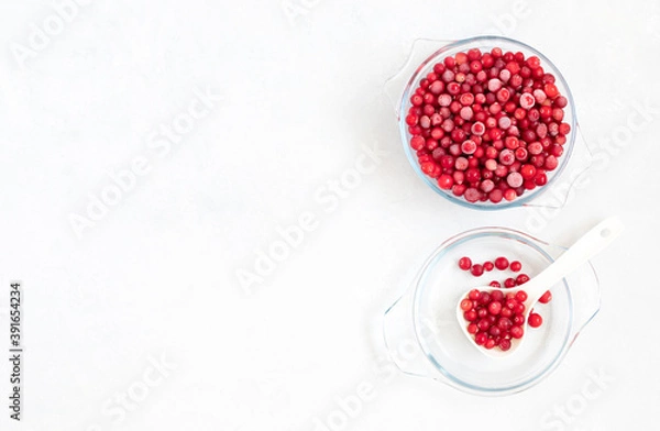 Fototapeta Frozen cranberry berries in a transparent bowl on a white background. Healthy food concept. Copy space, top view.