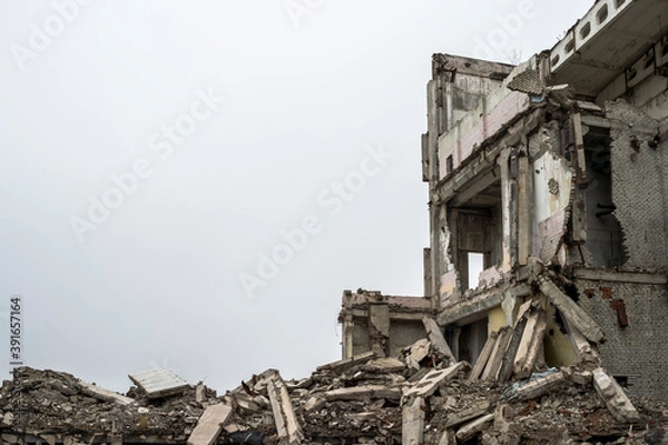 Fototapeta A ruined building with a pile of concrete gray debris against a neutral gray sky in a hazy haze. Background