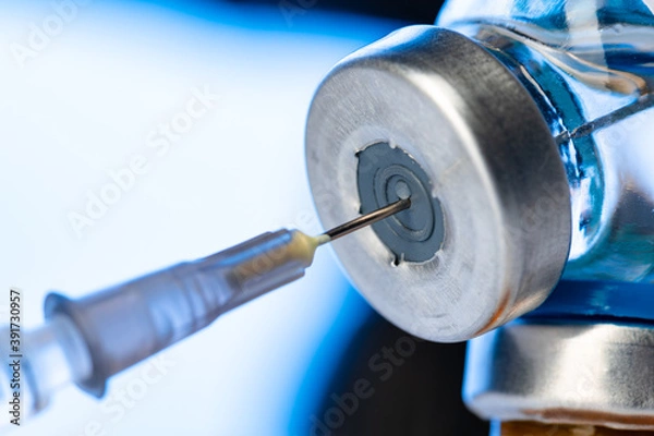 Fototapeta Vaccine bottle with a syringe taking the vaccine from it