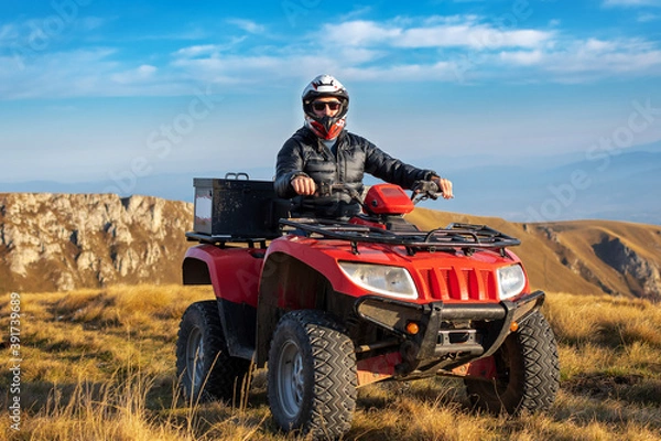Obraz A man on a quad bike in the mountains. 