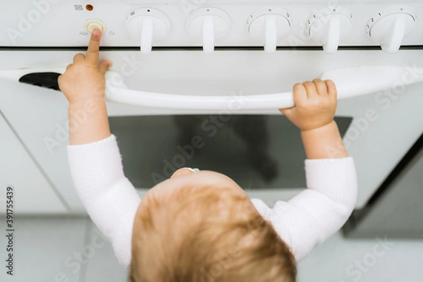 Obraz a boy playing with the oven in the kitchen Children in danger, risks at home.