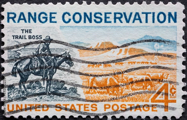 Fototapeta USA - Circa 1961 : a postage stamp printed in the US showing a cowboy on horseback. Pasture in the countryside. Text: Range Conservation. Trail boss