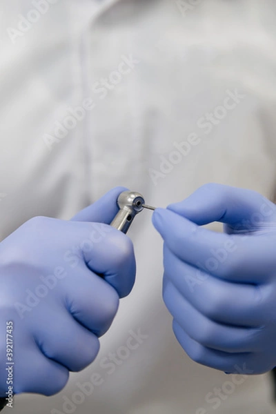 Obraz The dentist inserts the pin into the drill