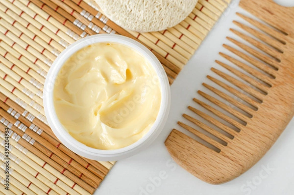 Fototapeta Yellow facial mask (banana face cream, shea butter hair mask, body butter) in the small white container. Natural skin and hair concept. Top view, copy space.