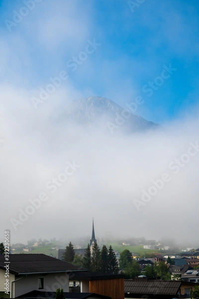 Fototapeta Disappearing fog over an Austrian village in the Alps