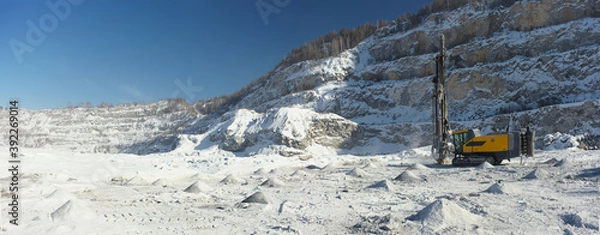 Obraz Mobile drilling machine in the snow-covered stone quarry in a winter sunny day, panorama.