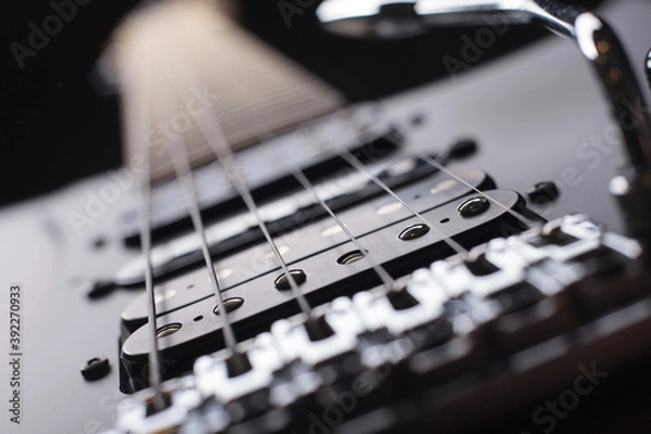 Obraz Elegant electric guitar on black background close up point of view from bridge to neck focused on bridge and humbucker pickups with silver tremolo