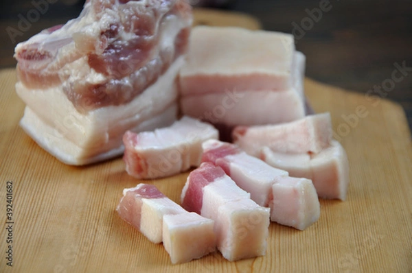 Fototapeta Pieces of fresh pork fat on a wooden board. Close-up
